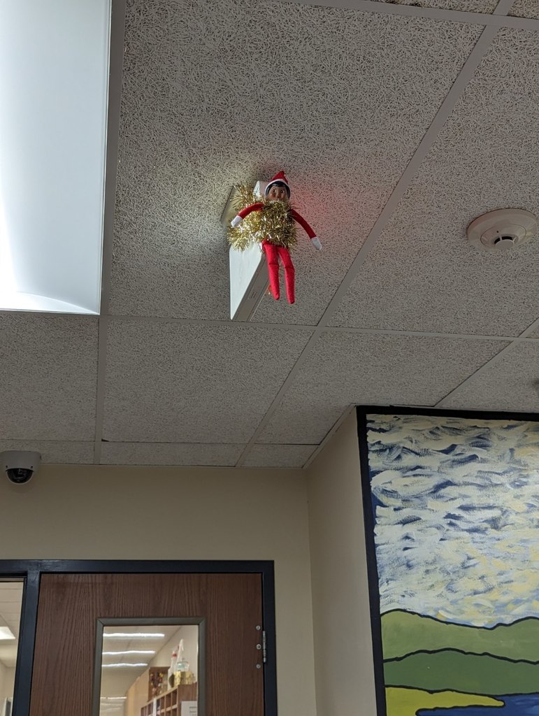 School elf hanging from an exit sign. 