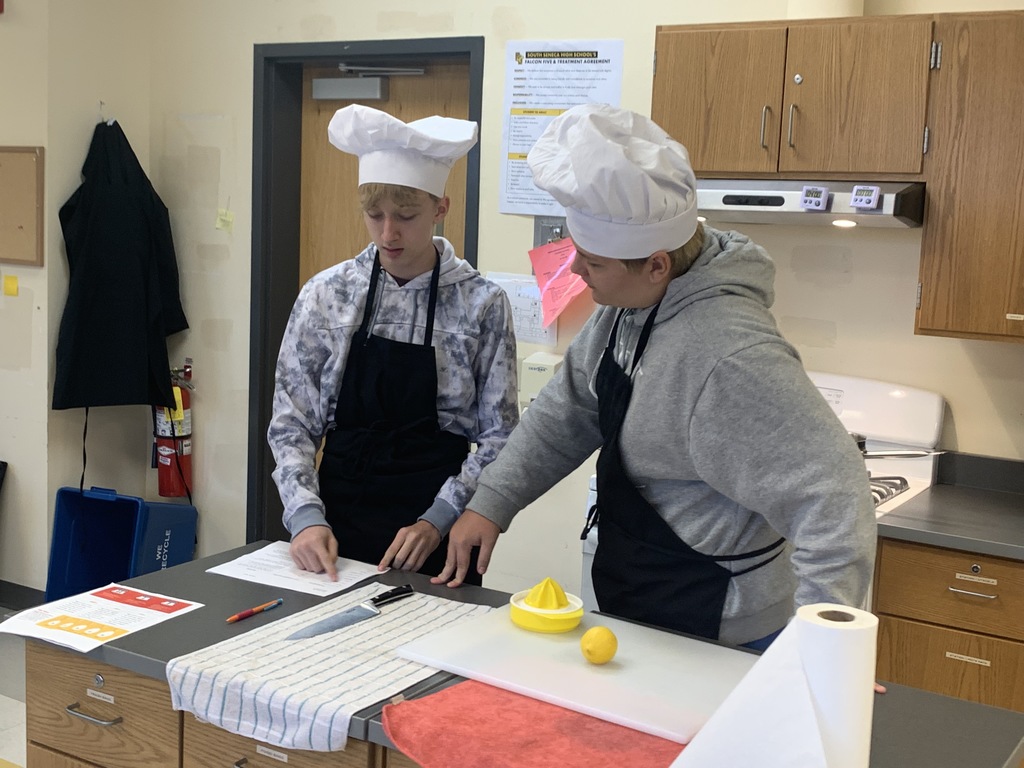 Students confer the recipe before preparing their dish.